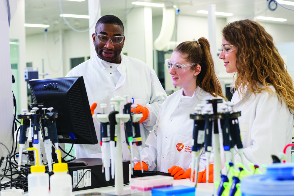 Three scientists in a GSK lab looking at a computer screen